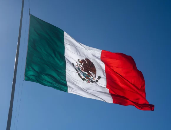 A low angle shot of the Mexican Flag waving on a sunny day in Mazatlan La Bandera Mexicana: Símbolo de Unidad en Tiempos de División